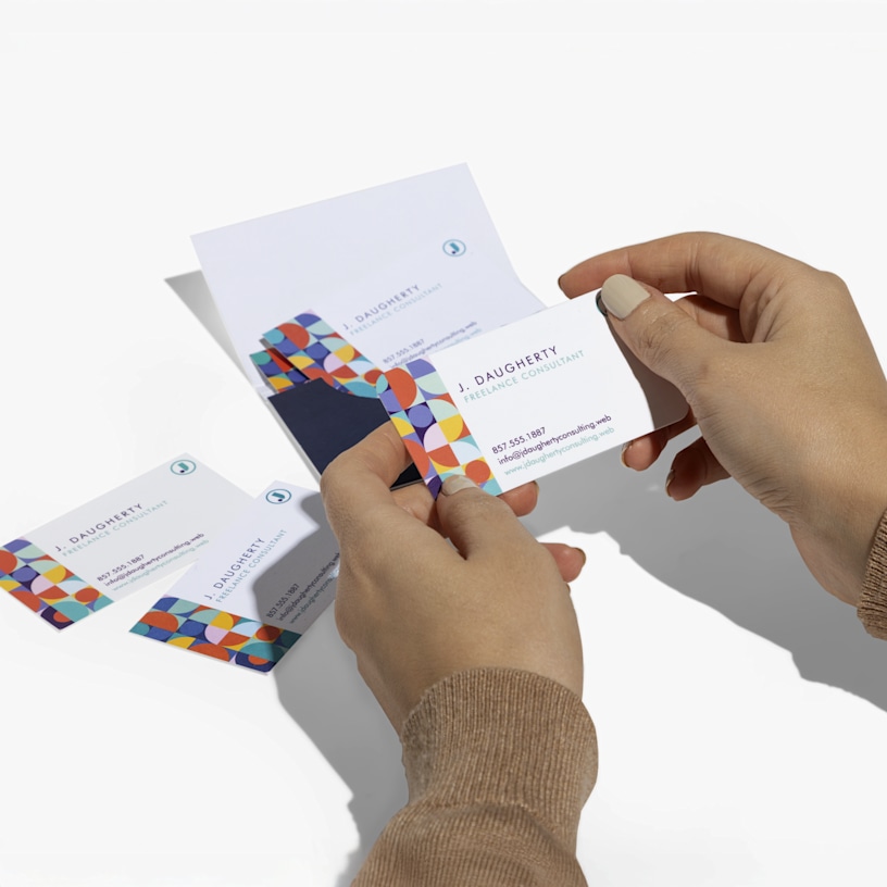 Two hands holding and comparing business cards against a clean white background, highlighting card thickness and finish.