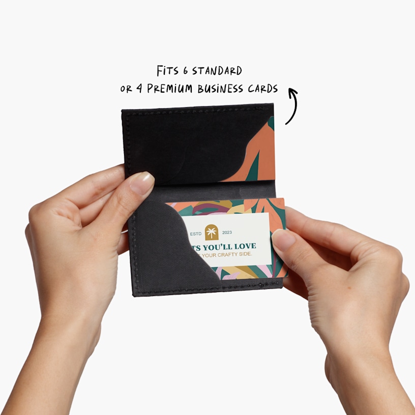 A person holding a slim black business card holder.