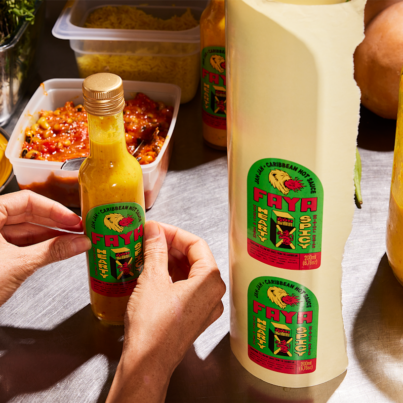 A person applying large rectangular labels from a roll onto boxes of natural skincare products.