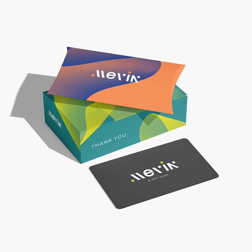 A brightly colored pillow and mini gift card box stacked on top of each other next to a gift card.