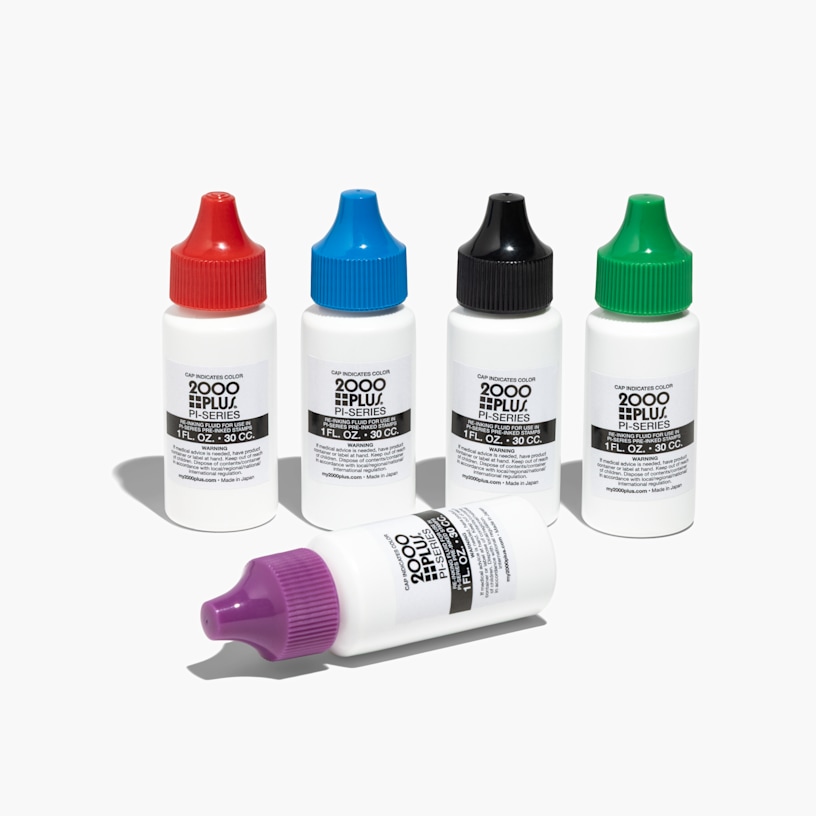 A red stamp pad outside of its case alongside a bottle of blue refill ink.