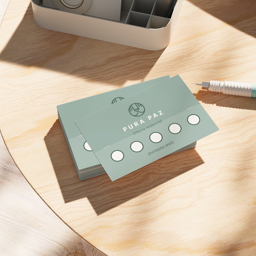 Una pila de tarjetas de fidelidad de un spa sobre una mesa de madera y junto a un bolígrafo.