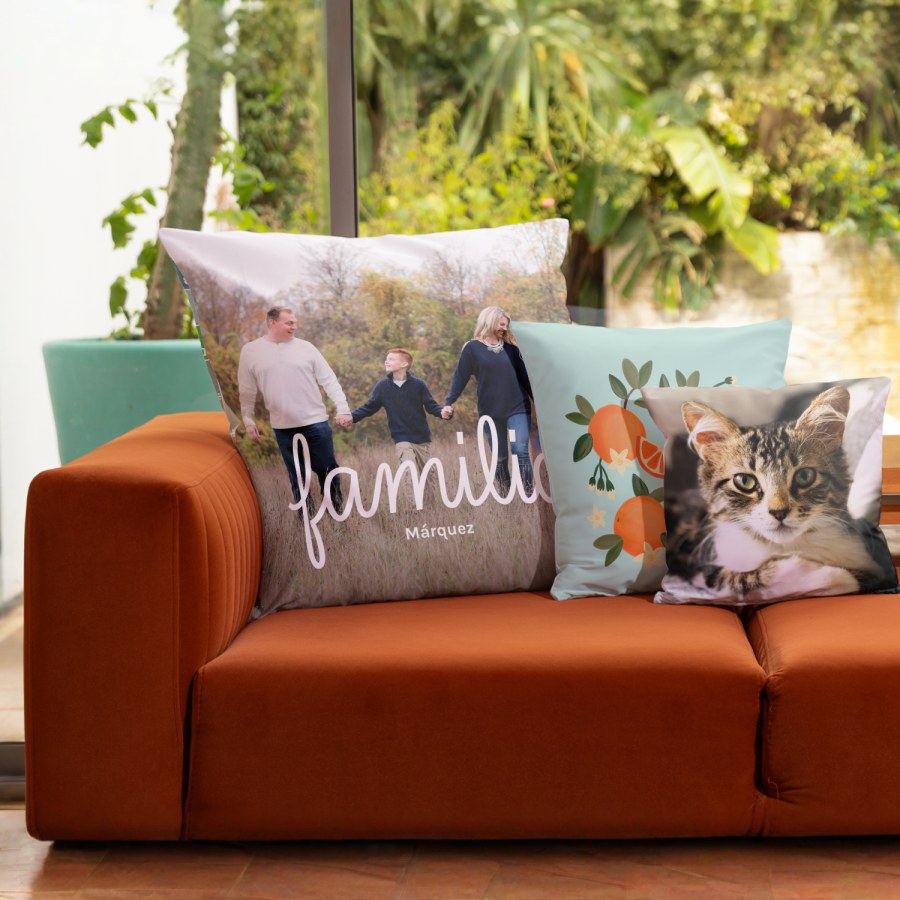 Tres cojines personalizados con una foto de familia, un diseño gráfico con naranjas y la foto de un gato. 