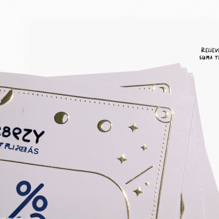 Primer plano de una tarjeta de visita con un logotipo y texto con relieve metalizado dorado.