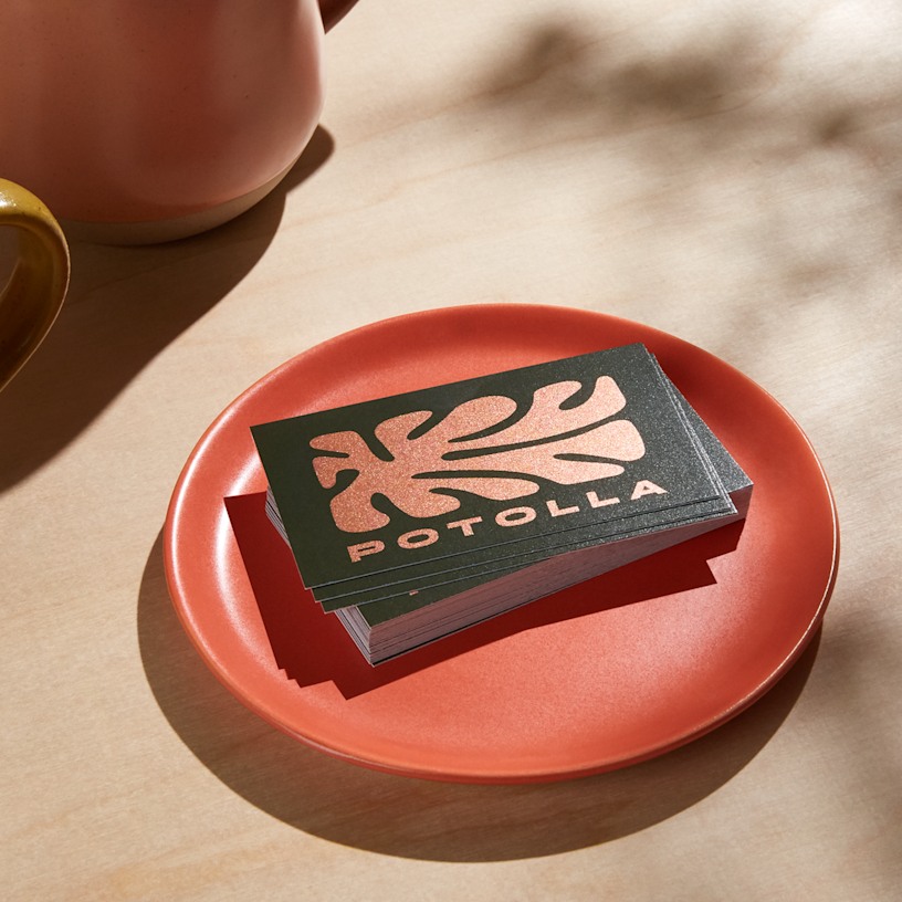 Tarjetas de visita con efecto metálico de Potolla, apiladas en un plato rojo.