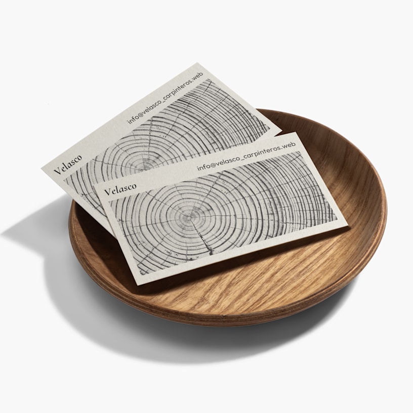 Dos tarjetas de visita de bambú para una empresa de carpintería sobre un cuenco de madera.