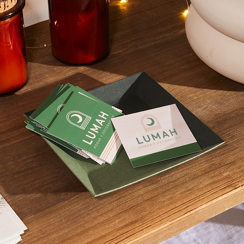 Una pila de tarjetas de visita cuadradas con acabado mate para una empresa de productos para el hogar colocadas sobre un cuenco.