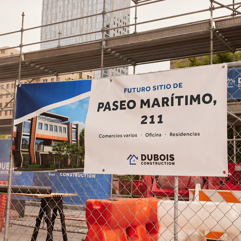 Una lona de una empresa de construcción colgada de la valla de una obra, en la que aparecen detalles sobre el nuevo edificio.
