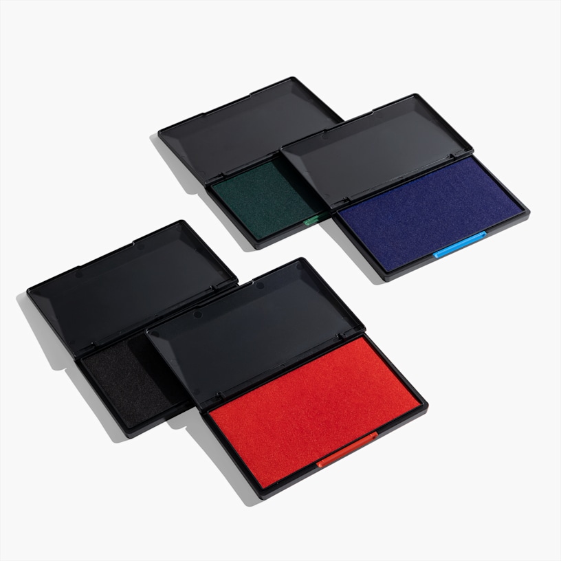 Cuatro almohadillas para sellos de tinta con las tapas abiertas que muestran sus colores: negro, verde, azul y rojo.