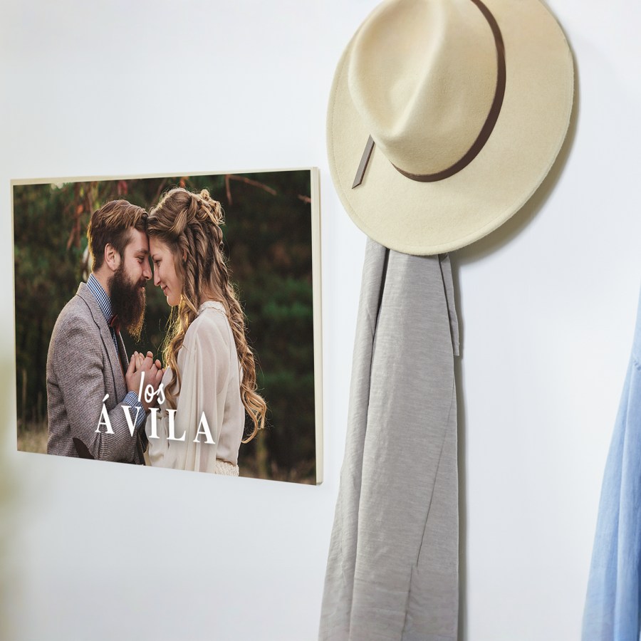 Una lámina en madera colgada en una pared con la foto de una pareja en su boda.
