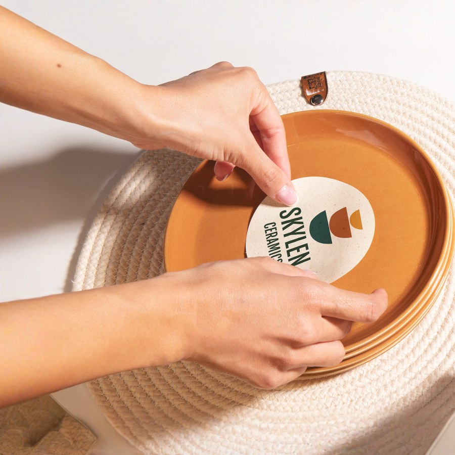 Una persona colocando en un plato una etiqueta para empaque de una empresa de cerámica.