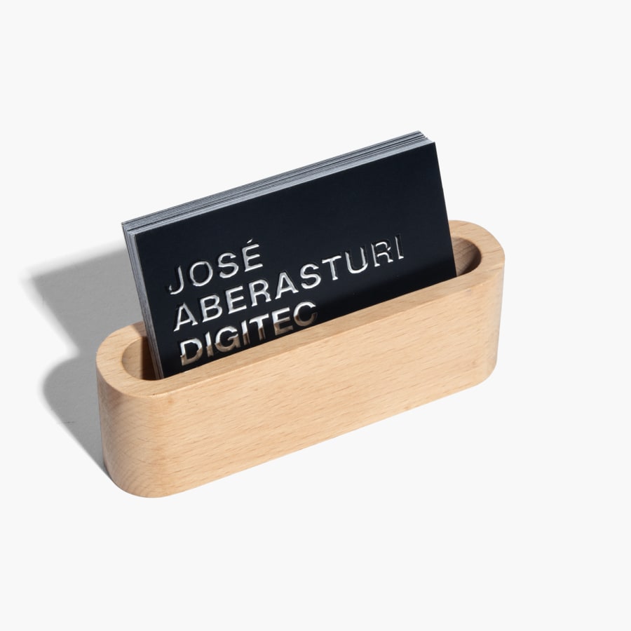 Tarjetas de presentación con relieves metalizados promocionando un estudio de fotografía, en un tarjetero de madera