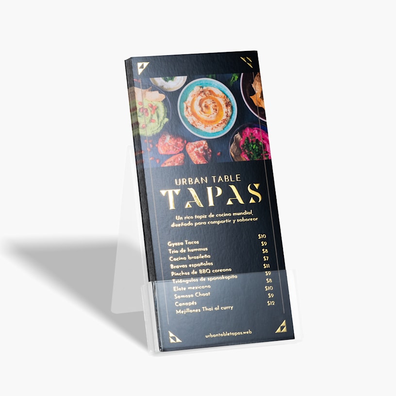Un conjunto de tarjetas informativas con relieves metalizados dorados con el menú de un restaurante, colocadas en un soporte plástico.