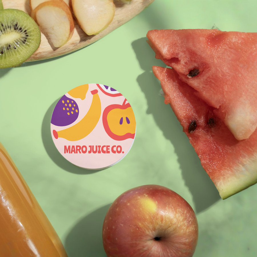 A stack of circle business cards for a juice company. The circle cards are sitting next to fresh fruits and a bottle of juice.