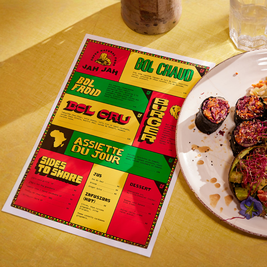 Un menú plano y colorido en un puesto de la mesa de un restaurante, junto a un plato de comida. 