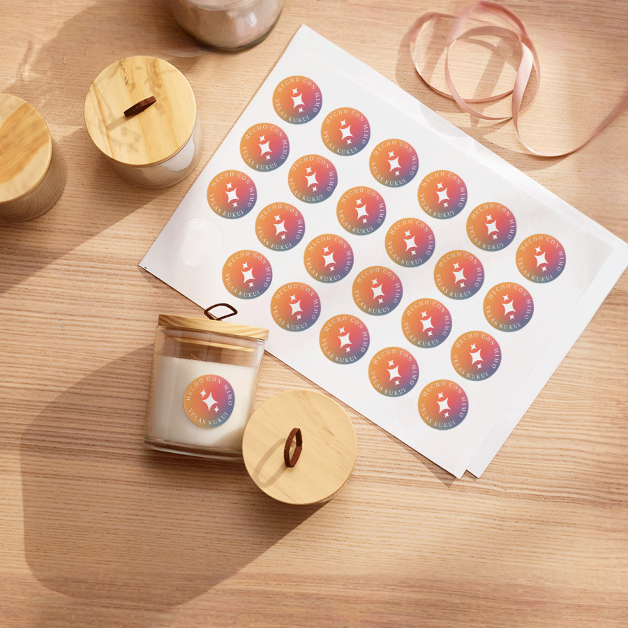 Una hoja de etiquetas de una empresa de velas, junto a unas velas que muestran las mismas etiquetas.