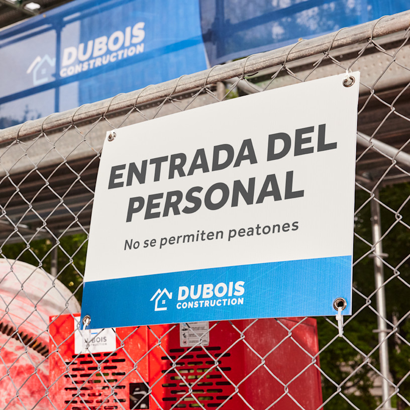 Un cartel para exteriores de una empresa de construcción con arandelas, colgado en una cerca.