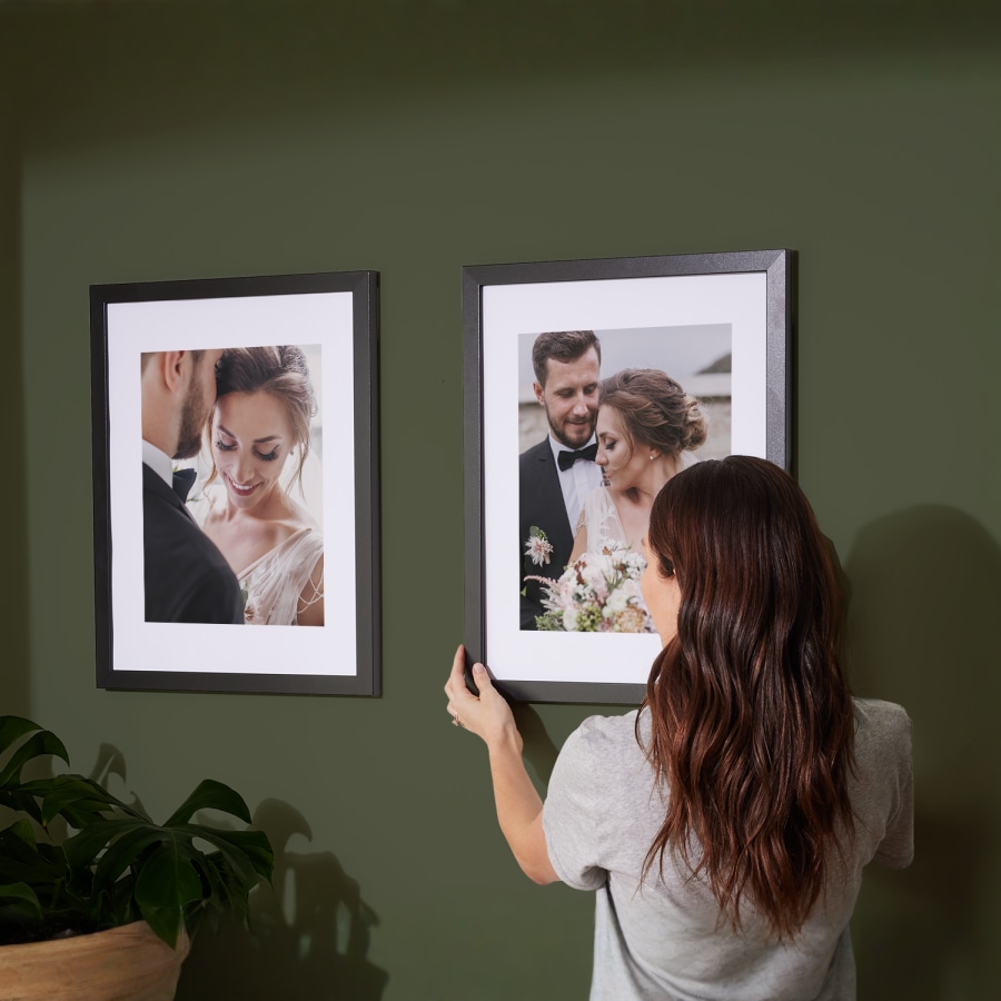 Dos fotos con marco colgadas en una pared, ambas mostrando fotos de boda. 
