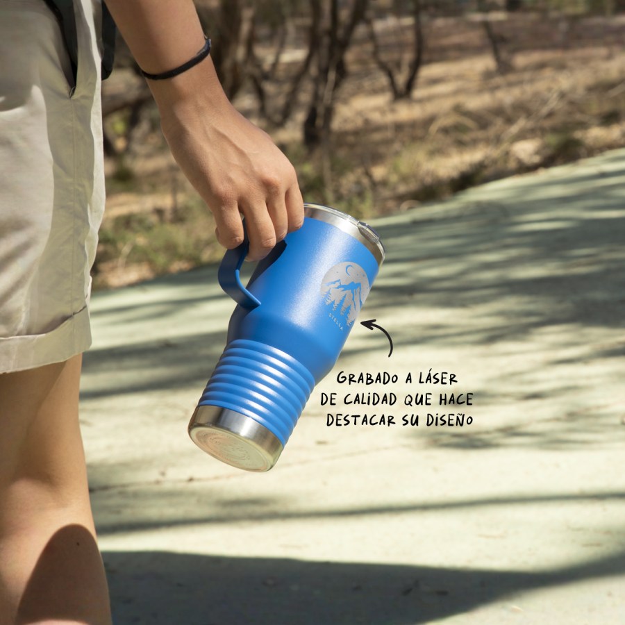Una taza de viaje azul personalizada en un paseo por la montaña. 
