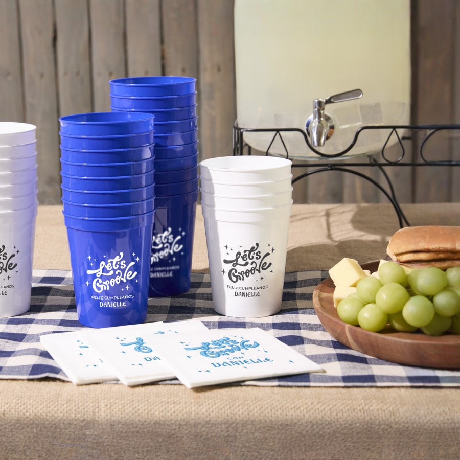 Vasos tipo estadio apilados en una mesa de fiesta, personalizados con el mensaje «Let's groove» (¡A bailar!).