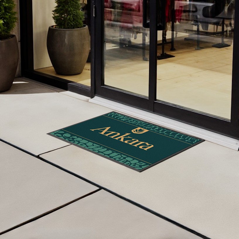 Un primer plano de un tapete con logo sobre un piso de mosaicos.