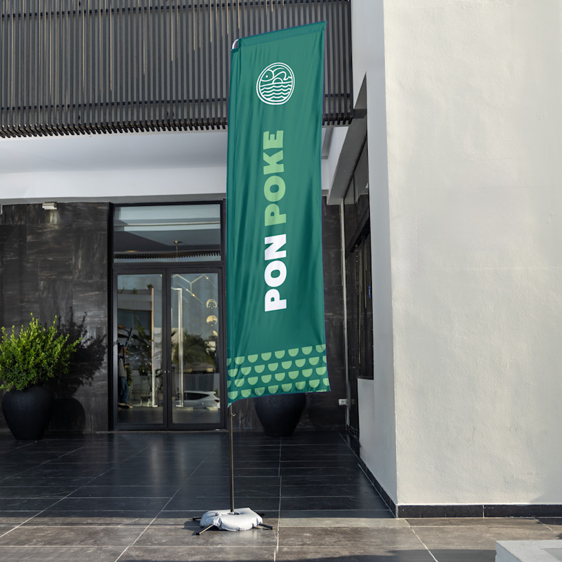 Una bandera rectangular verde de un restaurante de poke con una base para pavimento.  