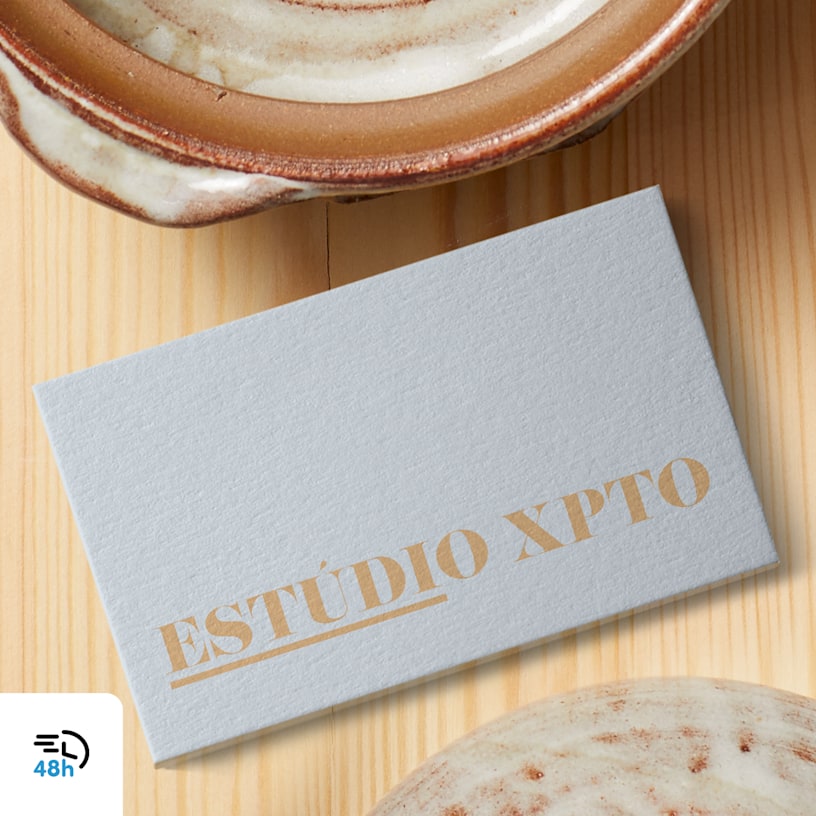 Una tarjeta de presentación texturizada color gris claro de un estudio de cerámica colocada en una superficie de madera cerca de una taza de cerámica, con el ícono de entrega en 48 horas en la esquina.