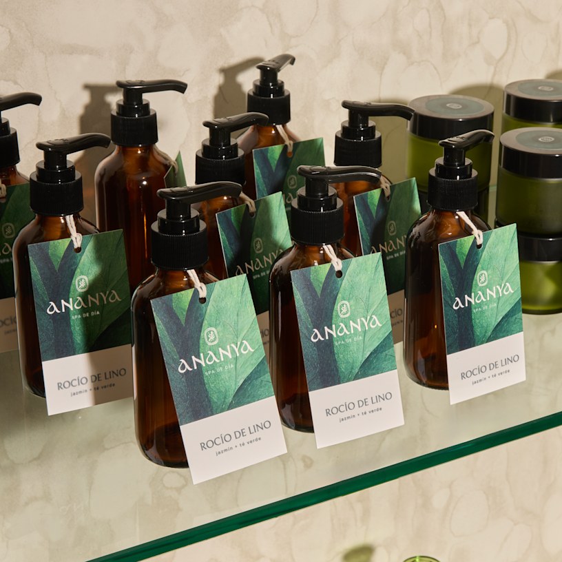Una variedad de etiquetas colgantes en botellas de jabón que promocionan una fragancia de bruma para ropa de cama.