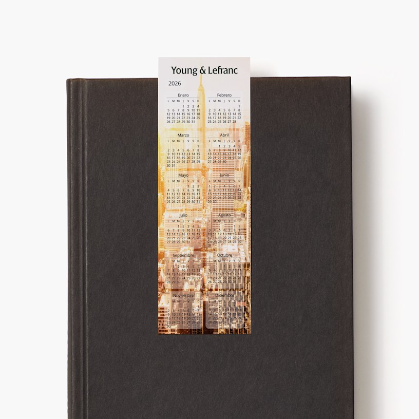 Un calendario marcapáginas del 2026 de una agencia que está colocado sobre un libro negro cerrado.