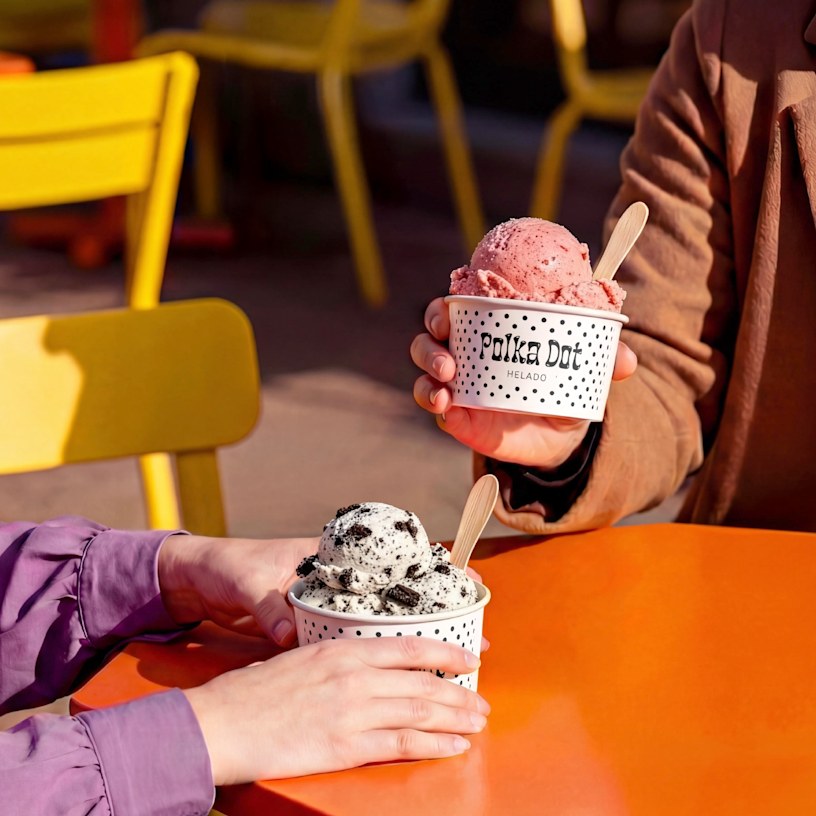2 vasos de papel con logotipos, con helado de fresa y de galletas y crema. 