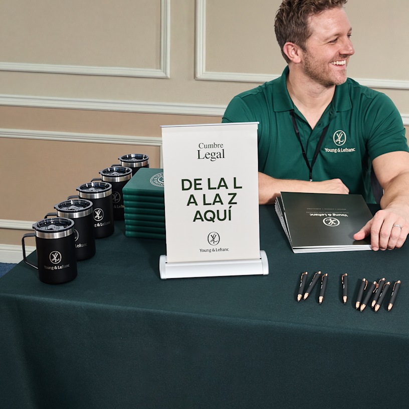  Una lona retráctil de mesa promocionando una cumbre legal en una feria comercial.