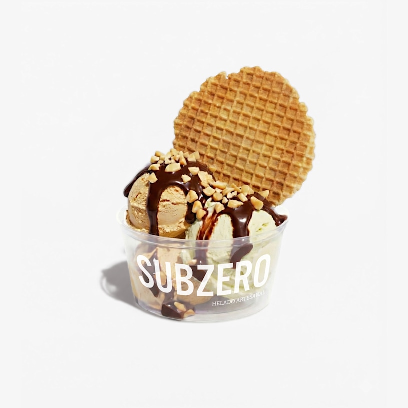 Un vaso plástico para helado con varias bolas de helado, nueces y topping de waffle.