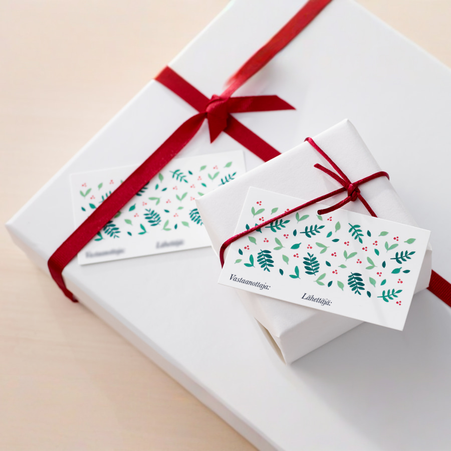 Paketoidun lahjan nauhan alle asetettu mukautettu lahjalappu, jossa on loma-aiheinen malli. 