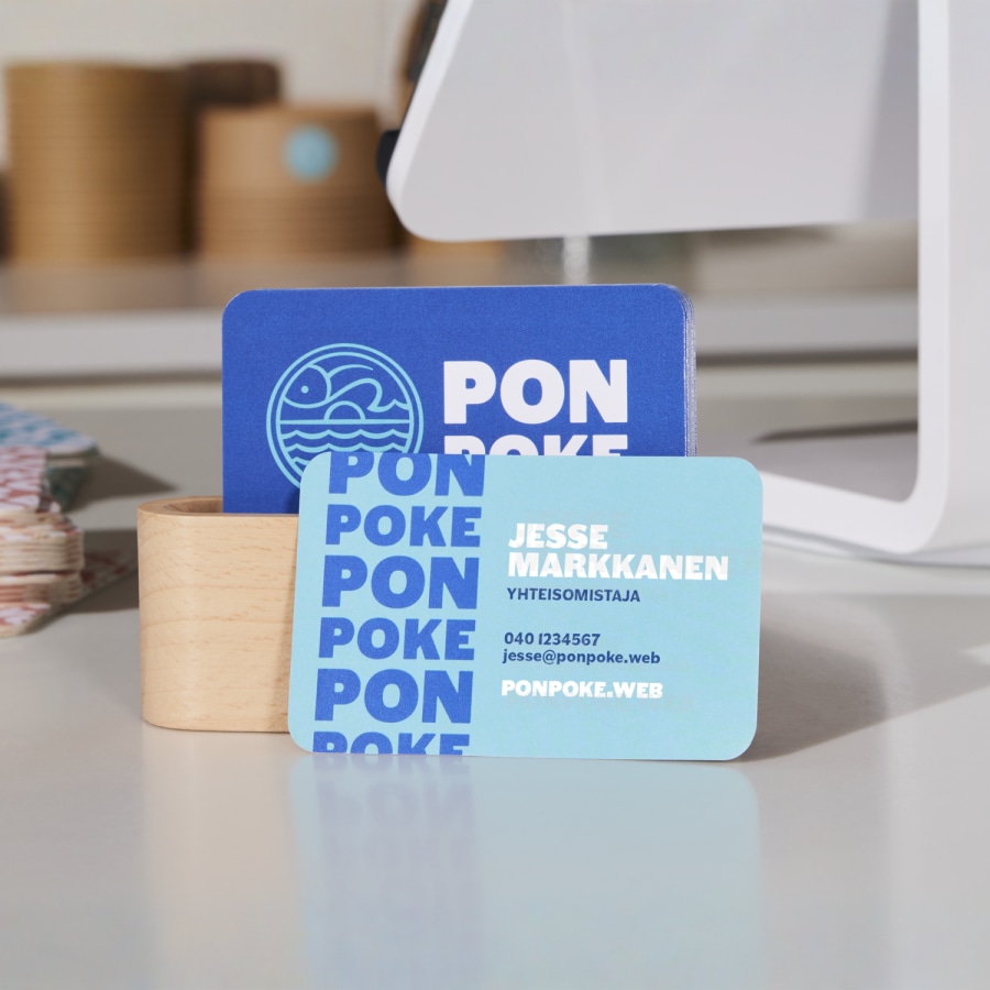 Setti poke-ravintolan sinivalkoisia käyntikortteja pyöristetyillä kulmilla​​ kassalle asetettuna.