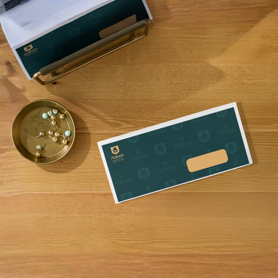 Enveloppe commerciale sur un bureau, ornée d’un logo dans le coin supérieur gauche avec un champ d’adresse visible sur le devant.