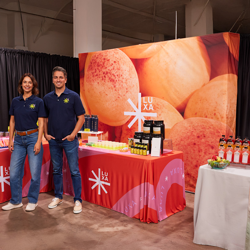 A man and a woman standing in front of a pop-up display at a tradeshow.