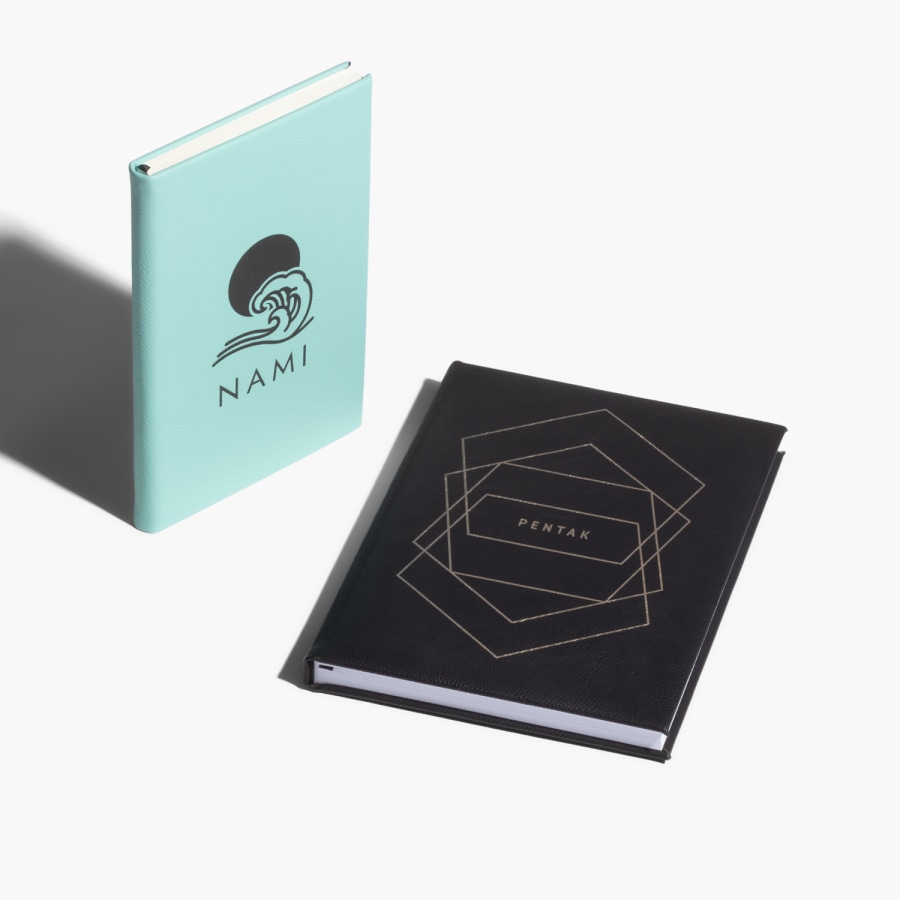 Deux carnets en similicuir, le plus petit appartient à une femme du nom de Nami, et le plus grand fait la promotion d'une entreprise de technologie.