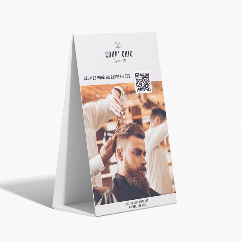 Panneau sur pieds en carton ondulé faisant la publicité d’un salon de coiffure, avec un code QR pour aider les clients à prendre rendez-vous.