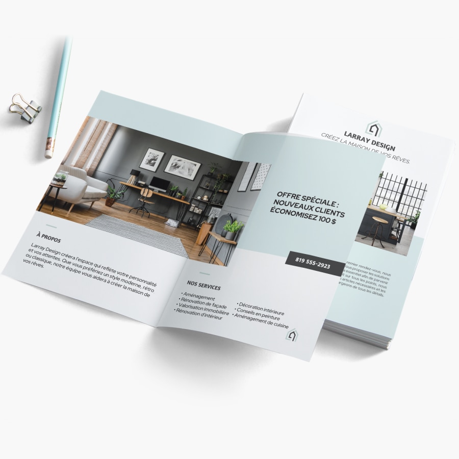 Un dépliant à deux volets conçu pour une entreprise de décoration intérieure repose ouvert sur une surface blanche, à proximité de fournitures de bureau.