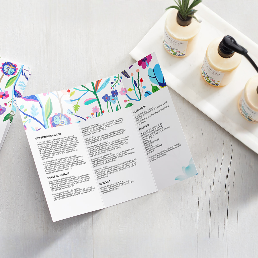 Dépliants à trois volets pour une entreprise de soins de la peau, sur une surface blanche à côté de produits de soins de la peau.