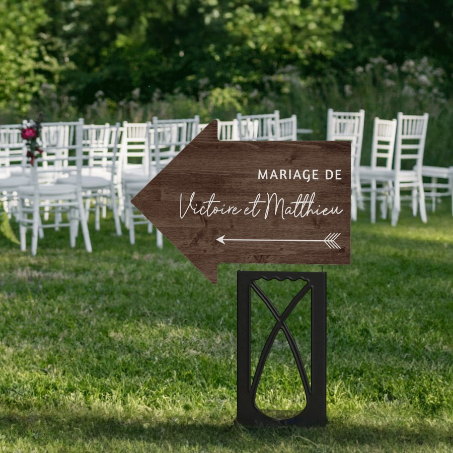 Une pancarte d’extérieur en forme de flèche, utilisée pour indiquer le plan de table d’un mariage.