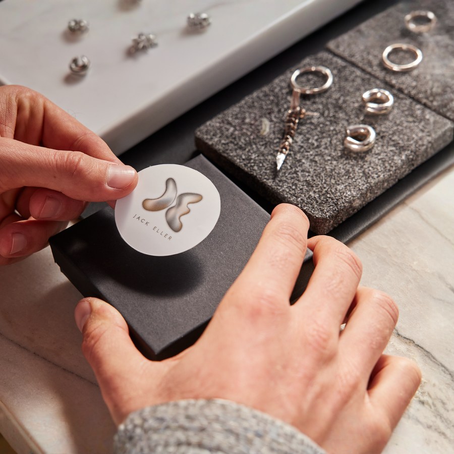 Une personne en train d’apposer une étiquette d’emballage ronde sur une boîte à bijoux.