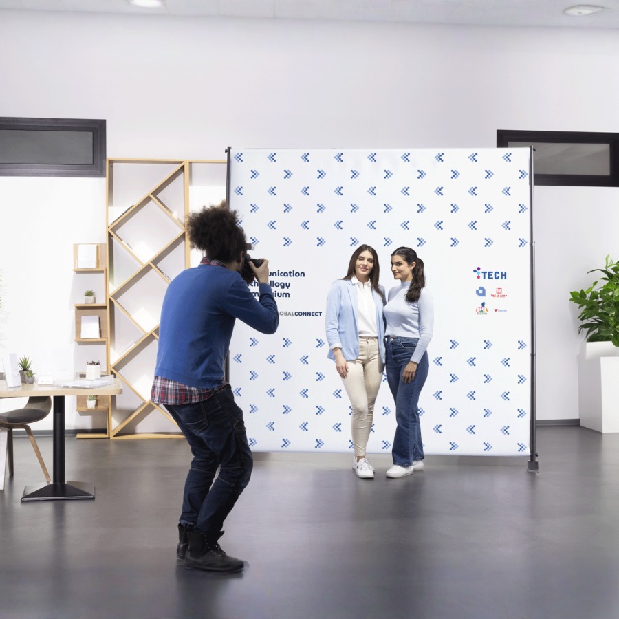 Deux femmes se faisant photographier devant une toile de fond reliée aux technologies.