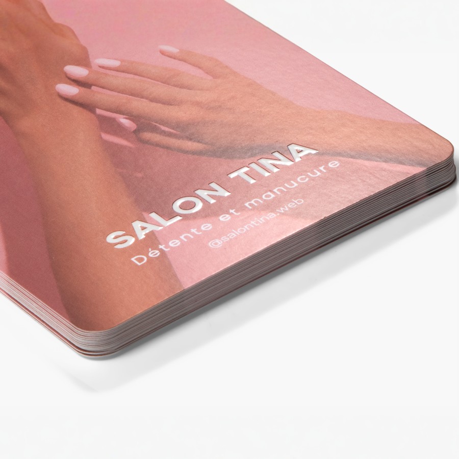 Une petite pile de cartons d’information brillants en relief, faisant la promotion d'un salon de manucure.