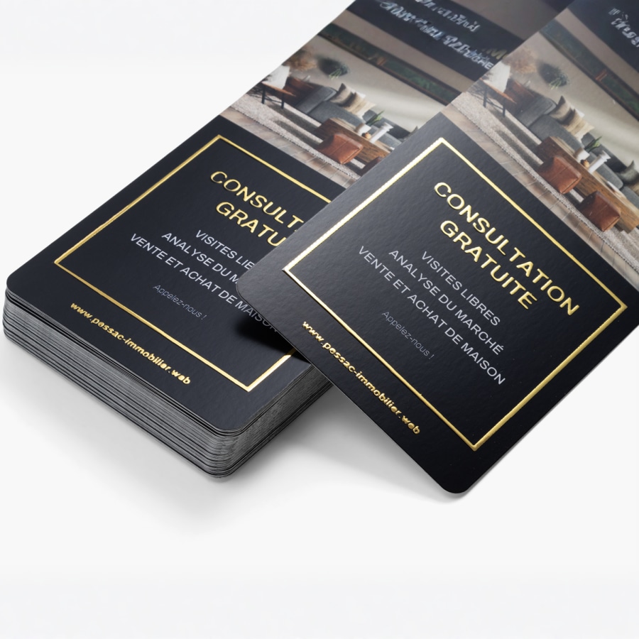 Pile de cartons d’information avec effet métallisé doré en relief pour une agence immobilière annonçant une consultation gratuite. 