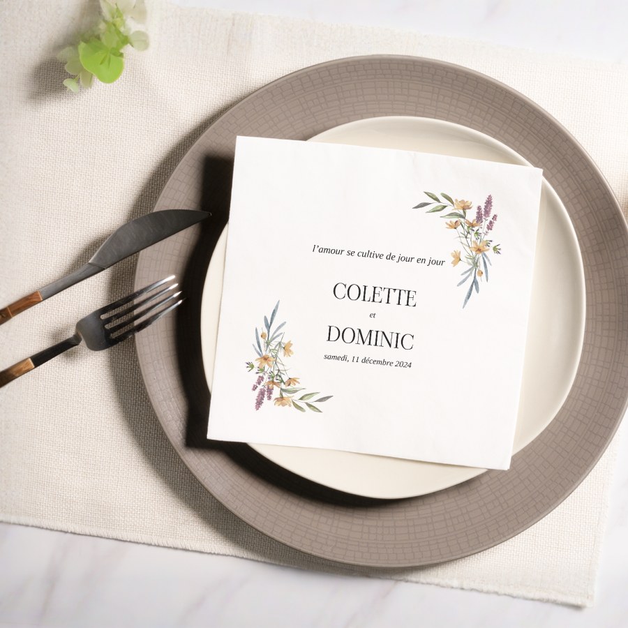 Une serviette de table florale personnalisée pour un mariage, avec les noms du couple et la date du mariage. 
