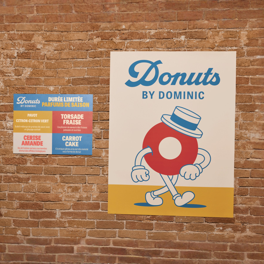 Une affiche horizontale et une verticale côte à côte sur un mur de briques présentant une boutique de beignes.