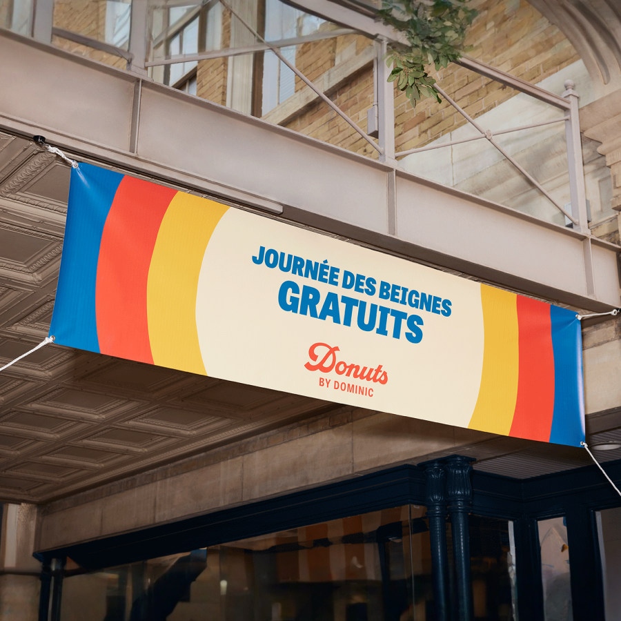 Une banderole colorée en vinyle, suspendue et faisant la promotion de beignes gratuits.