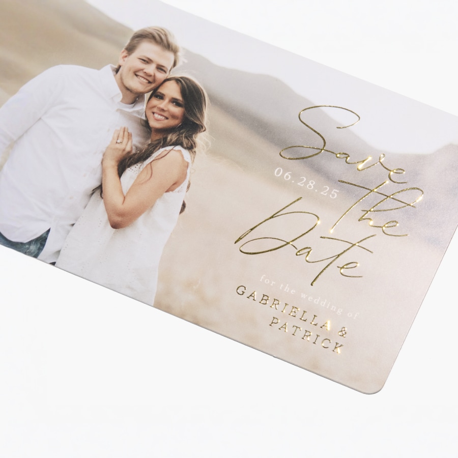 Une carte « Réservez la date » personnalisée présentant une photo d’un couple et des détails à effet métallisé en relief. 