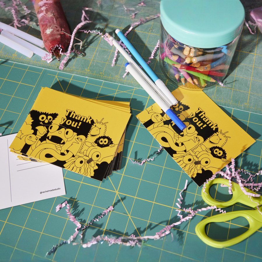 Une pile de cartes postales de remerciement posées sur une table de dessin.